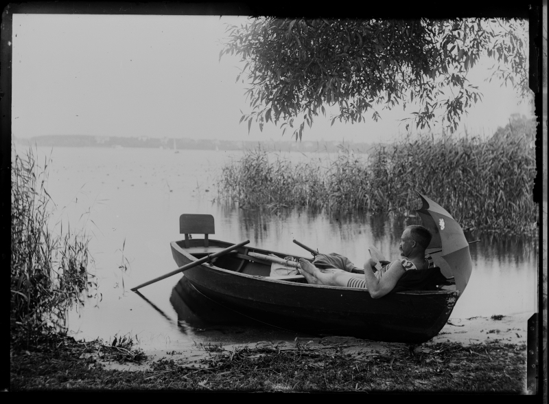Mann, lesend mit Schirm im Boot